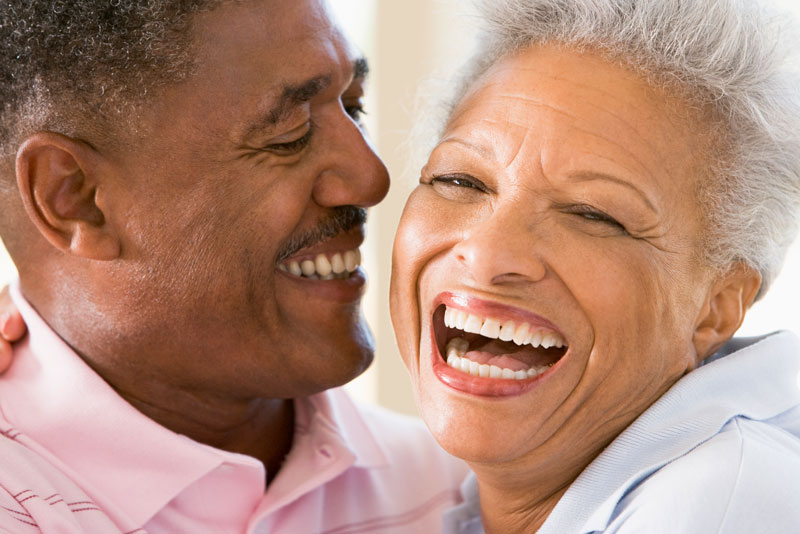 Happy senior couple laughing and smiling together, showcasing healthy teeth and the confidence that comes with restored dental function.